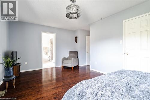 Hardwood flooring throughout featuring light gray walls, a white paneled door, and a decorative ceiling light fixture - 106 Moore Crescent, Ancaster, ON 