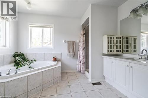 Bathroom featuring a corner built-in tub with tile surround, white vanity cabinetry, a shower stall, and light tile flooring - 106 Moore Crescent, Ancaster, ON 