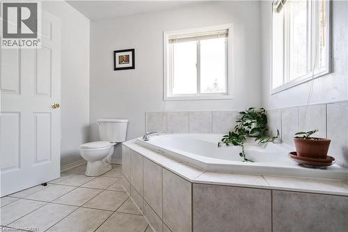 Corner soaking tub with a tiled surround, two windows, and a panel door - 106 Moore Crescent, Ancaster, ON 