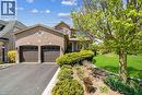 Brick facade residence featuring an attached two-car garage with panel doors, a circular window accent, and a paved driveway - 106 Moore Crescent, Ancaster, ON 