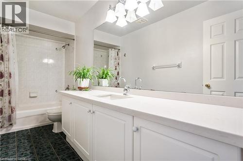 Bathroom featuring a double vanity with white cabinetry, a solid surface countertop, and dual sinks with chrome fixtures - 106 Moore Crescent, Ancaster, ON 