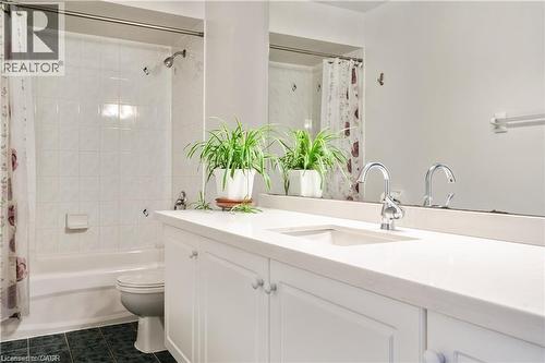 Bathroom featuring a white vanity with integrated sink, chrome faucet, and a large wall-mounted mirror - 106 Moore Crescent, Ancaster, ON 