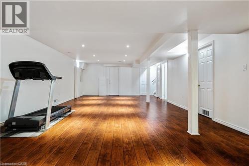 Spacious room featuring rich wood-finish flooring, recessed lighting, white walls, and multiple panel doors - 106 Moore Crescent, Ancaster, ON 