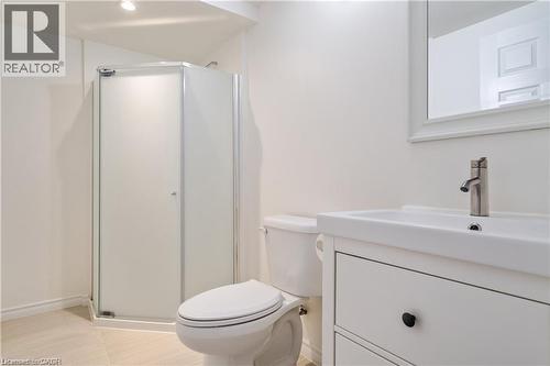 White bathroom featuring a glass-enclosed corner shower with frosted panels, a modern white vanity with an integrated sink, a brushed nickel faucet, and a wall-mounted mirror - 106 Moore Crescent, Ancaster, ON 