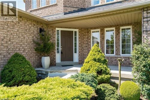 Brick exterior with a covered front entryway, white trim windows, and landscaped plantings - 106 Moore Crescent, Ancaster, ON 