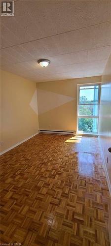 Bright room featuring wood-finish parquet flooring and a large window - 105 Conroy Crescent Unit# 505, Guelph, ON 