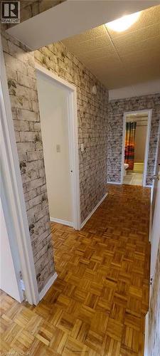 Hallway featuring wood-finish parquet flooring, faux brick wall treatment, and white trim - 105 Conroy Crescent Unit# 505, Guelph, ON 