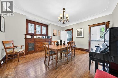 Dining area featuring wood-finish flooring, a built-in wooden buffet with leaded glass accents, and a classic chandelier - 35 Burris Street, Hamilton, ON - Indoor Photo Showing Dining Room