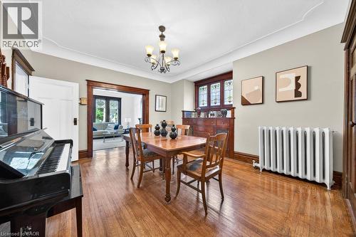Dining area featuring wood-finish flooring, a chandelier, and decorative crown molding - 35 Burris Street, Hamilton, ON - Indoor Photo Showing Dining Room