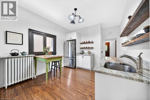 Kitchen featuring wood-finish flooring, white cabinetry, and a stainless steel refrigerator - 35 Burris Street, Hamilton, ON - Indoor Photo Showing Kitchen