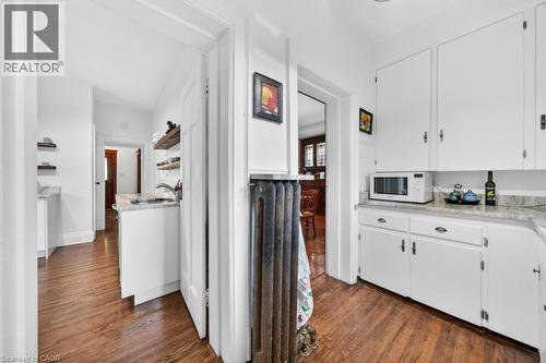 Kitchen featuring wood-finish flooring, white cabinetry, a stainless steel sink, and light-toned countertops - 35 Burris Street, Hamilton, ON - Indoor Photo Showing Kitchen