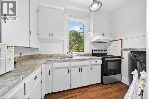 Kitchen featuring white cabinetry, stone-finish countertops, a stainless steel range, a coordinating range hood, and wood-finish flooring - 35 Burris Street, Hamilton, ON - Indoor Photo Showing Kitchen With Double Sink