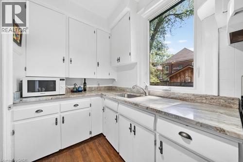 Kitchen featuring white cabinetry, a single basin sink with a chrome faucet, and wood-finish flooring - 35 Burris Street, Hamilton, ON - Indoor Photo Showing Kitchen