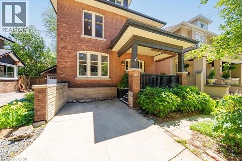 Brick exterior with white-framed windows, a covered front porch featuring dark columns, and a concrete driveway - 35 Burris Street, Hamilton, ON - Outdoor