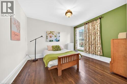 Hardwood flooring throughout featuring white baseboards, a single window with white trim, and a ceiling-mounted light fixture - 35 Burris Street, Hamilton, ON - Indoor Photo Showing Bedroom