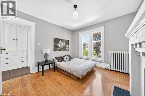 Hardwood flooring throughout featuring a white painted brick fireplace - 35 Burris Street, Hamilton, ON - Indoor Photo Showing Bedroom