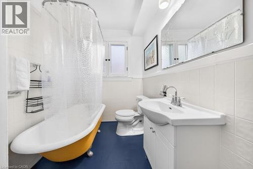 Bathroom featuring a yellow clawfoot tub, white subway tile surround, white vanity with integrated sink, chrome fixtures, and blue flooring - 35 Burris Street, Hamilton, ON - Indoor Photo Showing Bathroom