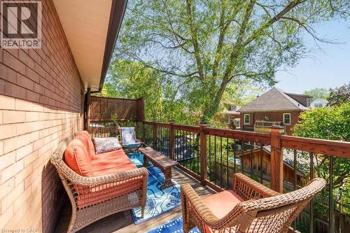 Outdoor deck space featuring wood railing with black spindles, brick-clad exterior wall, and overhead soffit - 35 Burris Street, Hamilton, ON - Outdoor With Exterior