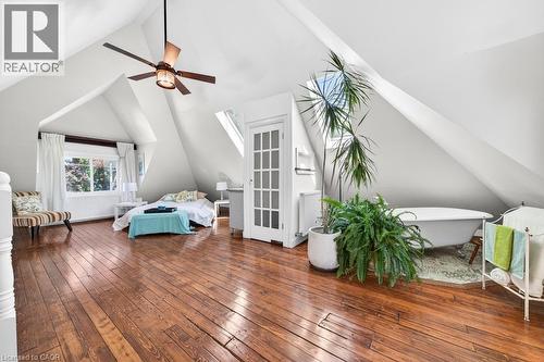 Spacious room featuring sloped ceilings, wood-finish flooring, and a freestanding clawfoot bathtub - 35 Burris Street, Hamilton, ON - Indoor Photo Showing Other Room