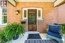 Brick exterior featuring a wood-panel entry door with decorative glass sidelights, an arched brick detail, and a wall-mounted light fixture - 35 Burris Street, Hamilton, ON  - Outdoor With Exterior 