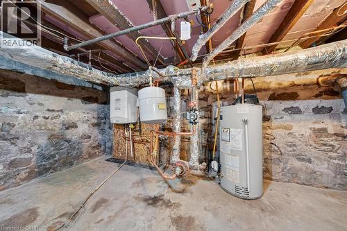 Basement utility area featuring a stone foundation, exposed wood joists, a water heater, and two wall-mounted units - 35 Burris Street, Hamilton, ON - Indoor Photo Showing Basement