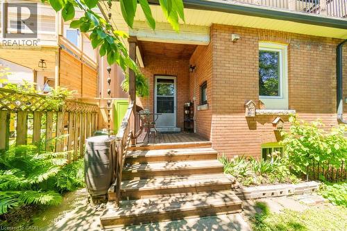 Rear deck with wood-finish steps and railing, brick exterior, and a lattice privacy fence - 35 Burris Street, Hamilton, ON - Outdoor With Exterior