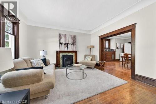 Living space featuring wood-finish flooring, a decorative fireplace with a tile surround, substantial wood trim, and crown molding - 35 Burris Street, Hamilton, ON - Indoor Photo Showing Living Room With Fireplace