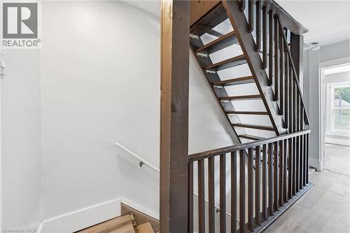 Stairwell featuring dark wood-finish balusters and handrail, with light-toned walls and wood-finish flooring extending into a loft storage space - 343 Cumberland Avenue, Hamilton, ON 