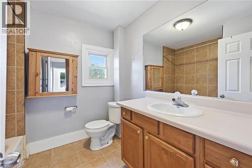 Full bathroom featuring a single window, tiled flooring, built-in medicine cabinet, and a vanity with a large mirror and integrated sink - 343 Cumberland Avenue, Hamilton, ON 