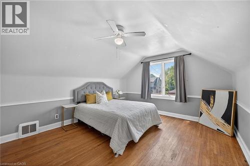 Room featuring wood-finish flooring, a ceiling fan, a window, and two-tone wall paint - 43 West 1St Street, Hamilton, ON 