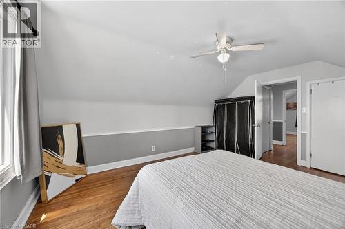 Attic room featuring wood-finish flooring, a ceiling fan, and a window with natural light - 43 West 1St Street, Hamilton, ON 