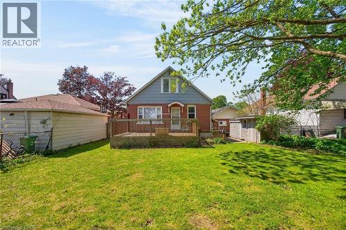Expansive backyard featuring a green lawn, wood deck, brick and siding exterior, and a detached structure - 43 West 1St Street, Hamilton, ON 