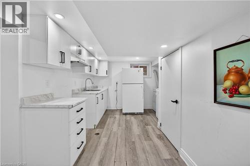 Kitchenette featuring white cabinetry with black hardware, light-toned countertops, and wood-finish flooring - 43 West 1St Street, Hamilton, ON 