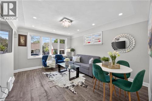 Open concept living area featuring wood-finish flooring, a tray ceiling with recessed lighting, and a modern chandelier - 43 West 1St Street, Hamilton, ON 