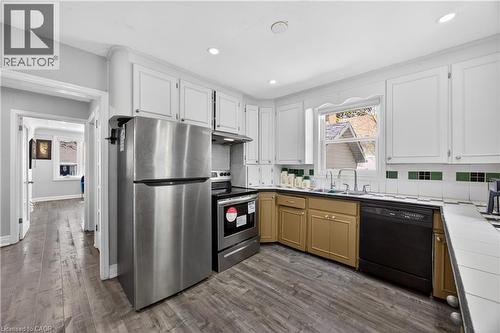Kitchen featuring stainless steel appliances, white cabinetry, wood-finish flooring, recessed lighting, and a window above the sink - 43 West 1St Street, Hamilton, ON 