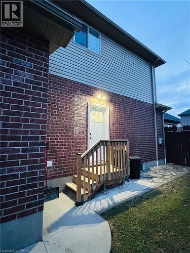 Rear exterior with brick and siding facade, featuring a wooden staircase leading to a white entry door - 1377 Coronation Drive, London, ON - Outdoor With Exterior