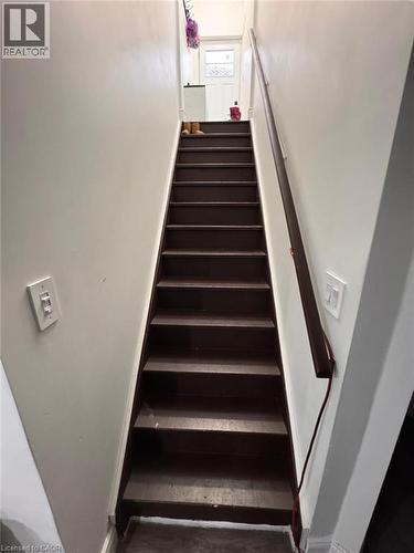 Staircase with dark-stained wood treads and a matching handrail, framed by light-colored walls - 1377 Coronation Drive, London, ON - Indoor Photo Showing Other Room