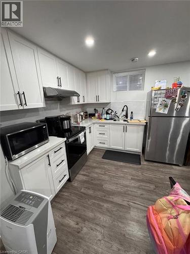 Modern kitchen featuring white shaker cabinetry with black hardware, stainless steel appliances, and wood-finish flooring - 1377 Coronation Drive, London, ON - Indoor Photo Showing Kitchen