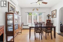 Bright interior space featuring light wood-finish flooring, a ceiling fan with integrated lighting, and multiple windows with blinds - 