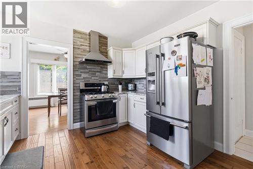 Kitchen featuring wood-finish flooring, white cabinetry, and stainless steel appliances - 134 Queensway Drive, Brantford, ON 