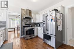 Kitchen featuring wood-finish flooring, white cabinetry, and stainless steel appliances - 