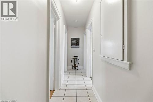 Hallway featuring square tile flooring, multiple doorways, and a wall-mounted panel with trim - 134 Queensway Drive, Brantford, ON 