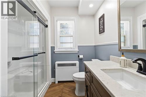 Bathroom featuring a vanity with an integrated sink, black hardware, a wood-finish cabinet, and a light-toned countertop - 134 Queensway Drive, Brantford, ON 