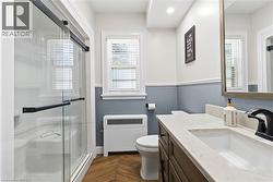 Bathroom featuring a vanity with an integrated sink, black hardware, a wood-finish cabinet, and a light-toned countertop - 