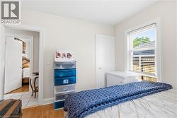 Room featuring wood-finish flooring, white painted walls, and a single window with blinds - 