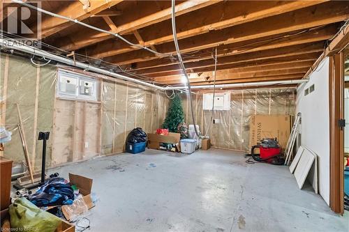 Unfinished basement space featuring exposed wood joists, concrete flooring, two windows, and an insulated wall with vapor barrier - 134 Queensway Drive, Brantford, ON 