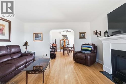 Hardwood flooring throughout, white walls, fireplace with white mantel and dark stone hearth, and an arched entryway - 134 Queensway Drive, Brantford, ON 