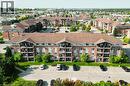 Brick multi-story building featuring multiple private balconies, a gabled roofline, and surrounding parking areas - 41 Goodwin Drive Unit# 202, Guelph, ON 