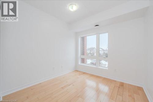 Bright room featuring a large window, light wood-finish flooring, white walls, white trim, and a ceiling-mounted light fixture - 41 Goodwin Drive Unit# 202, Guelph, ON 