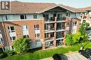 Multi-story residential building featuring a brick exterior with white siding accents and a brown shingle roof - 41 Goodwin Drive Unit# 202, Guelph, ON 